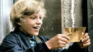 a screenshot of the charlie and the chocolate factory movie, where charlie is holding the golden ticket